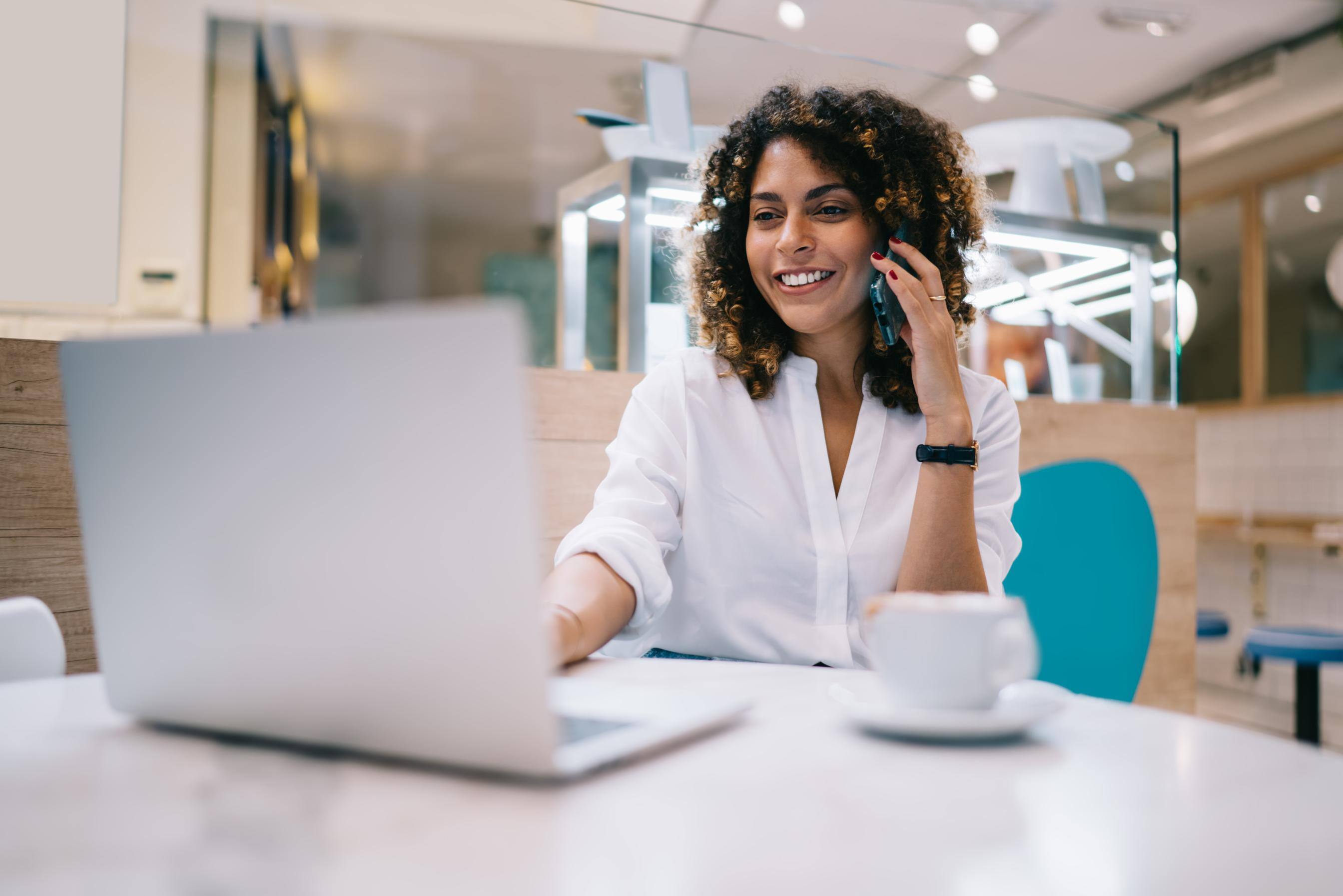 Business woman working on a laptop at a desk while talking on the phone