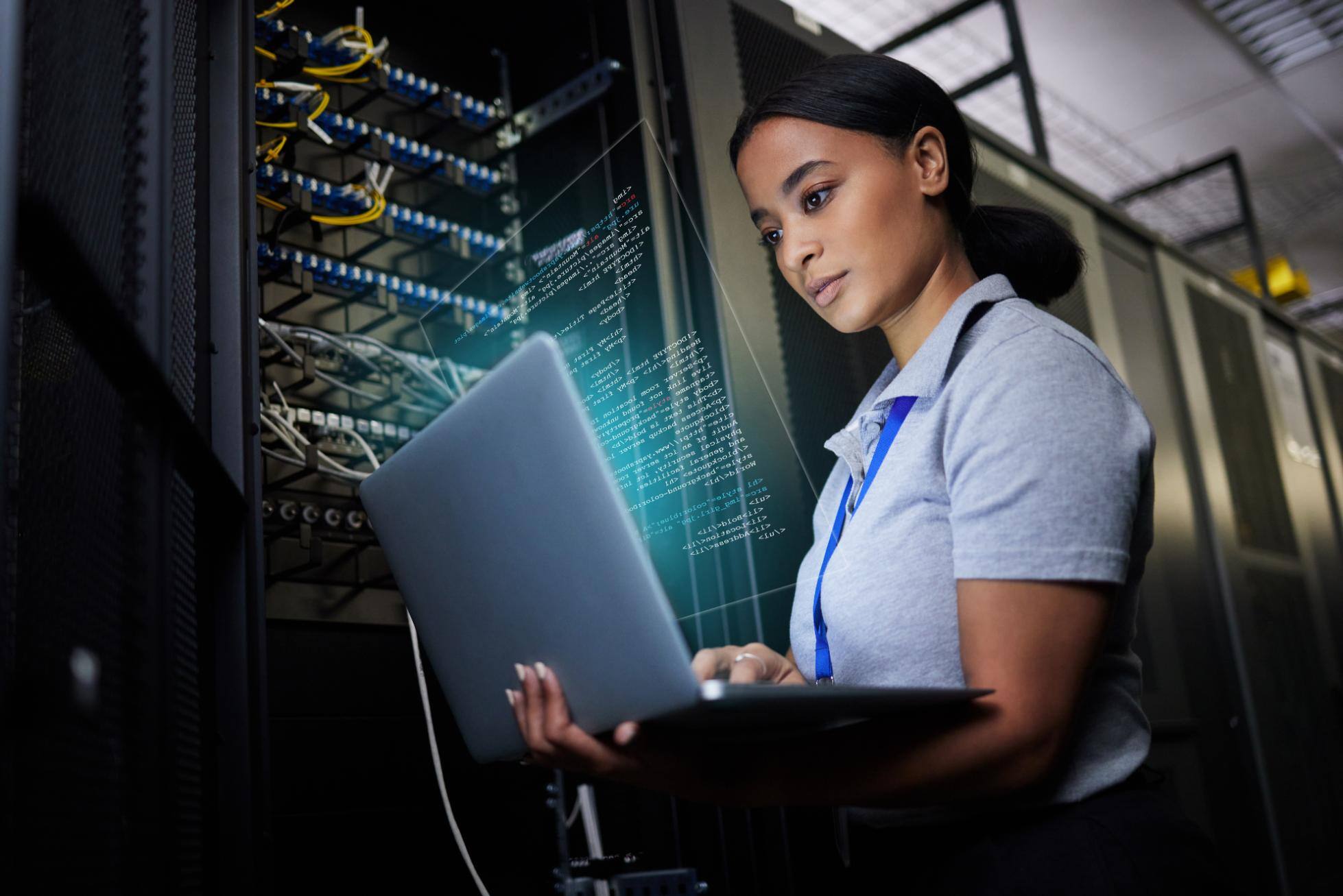 Business woman monitoring a network on a laptop in a data center