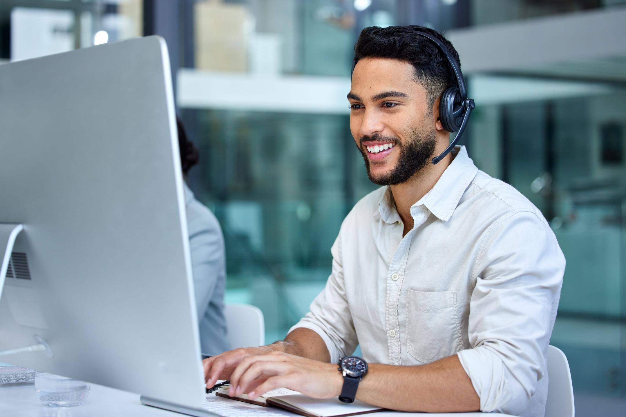 Business man talking on a heads set while typing on computer