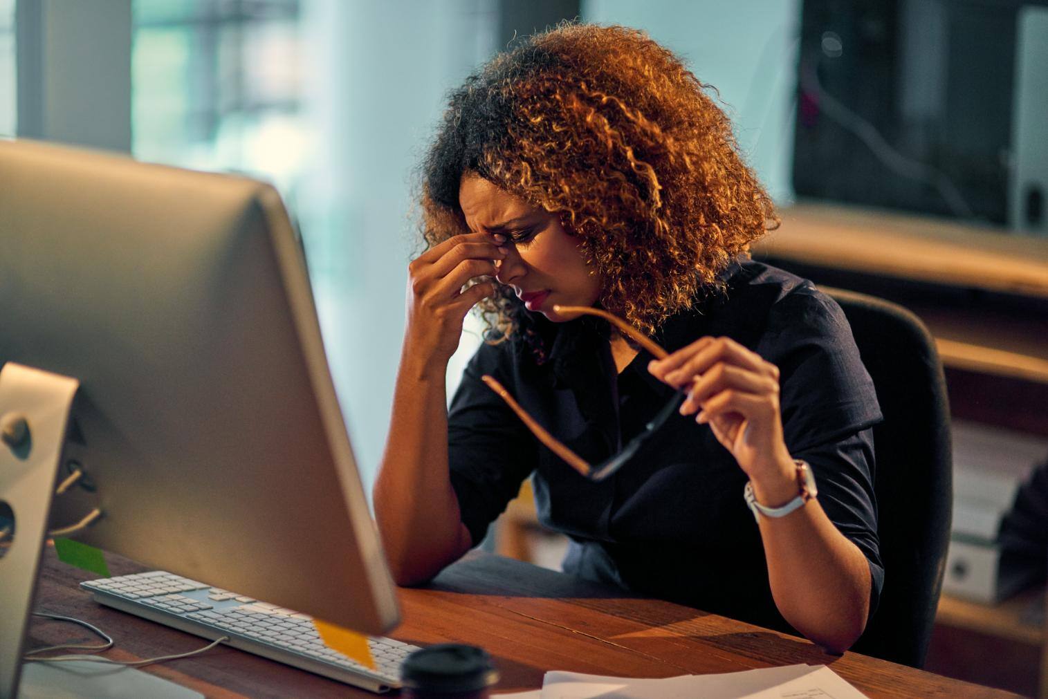 Business woman upset holding her head on a computer